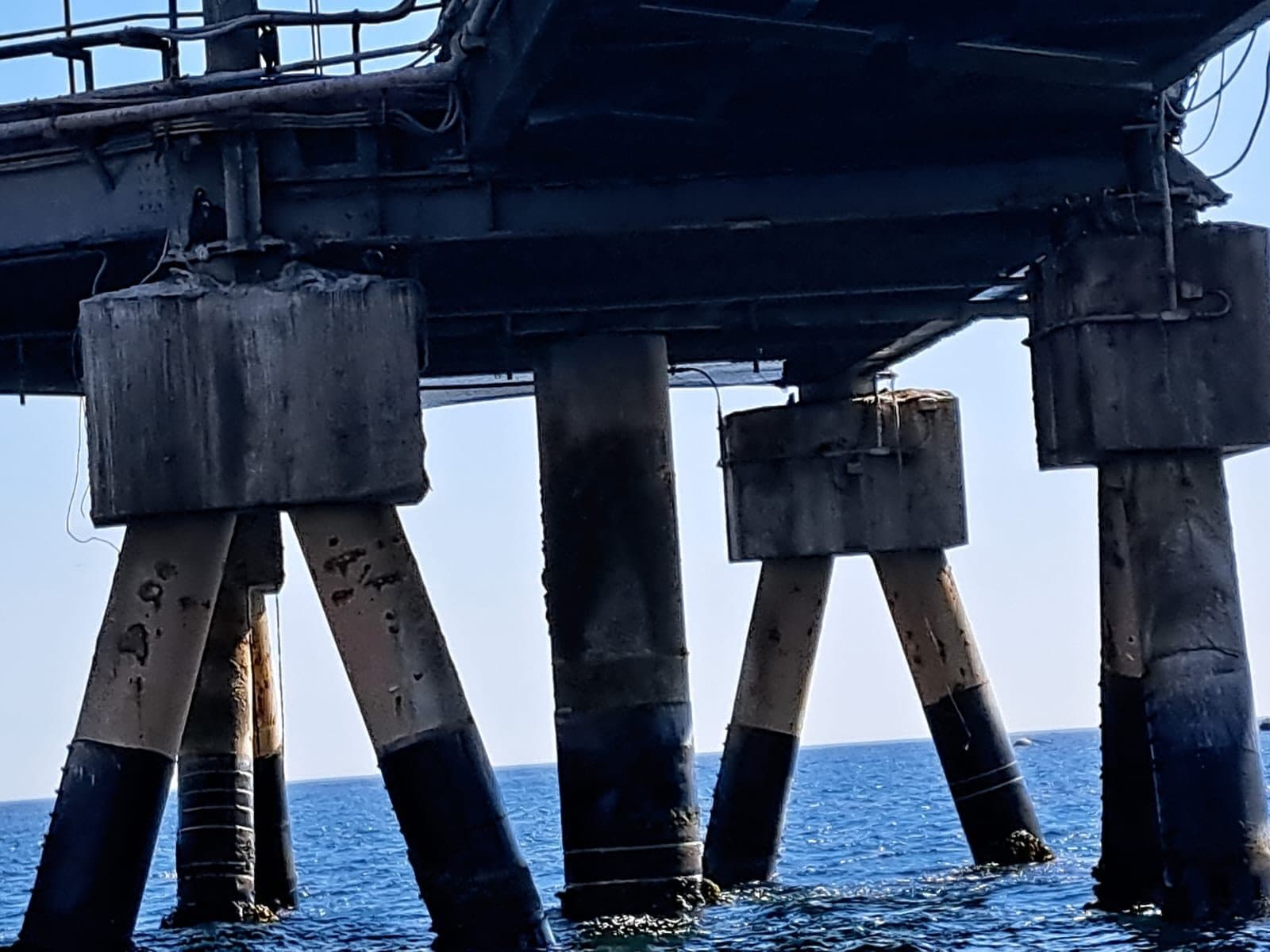 Piled jetty with anode sleeves over water