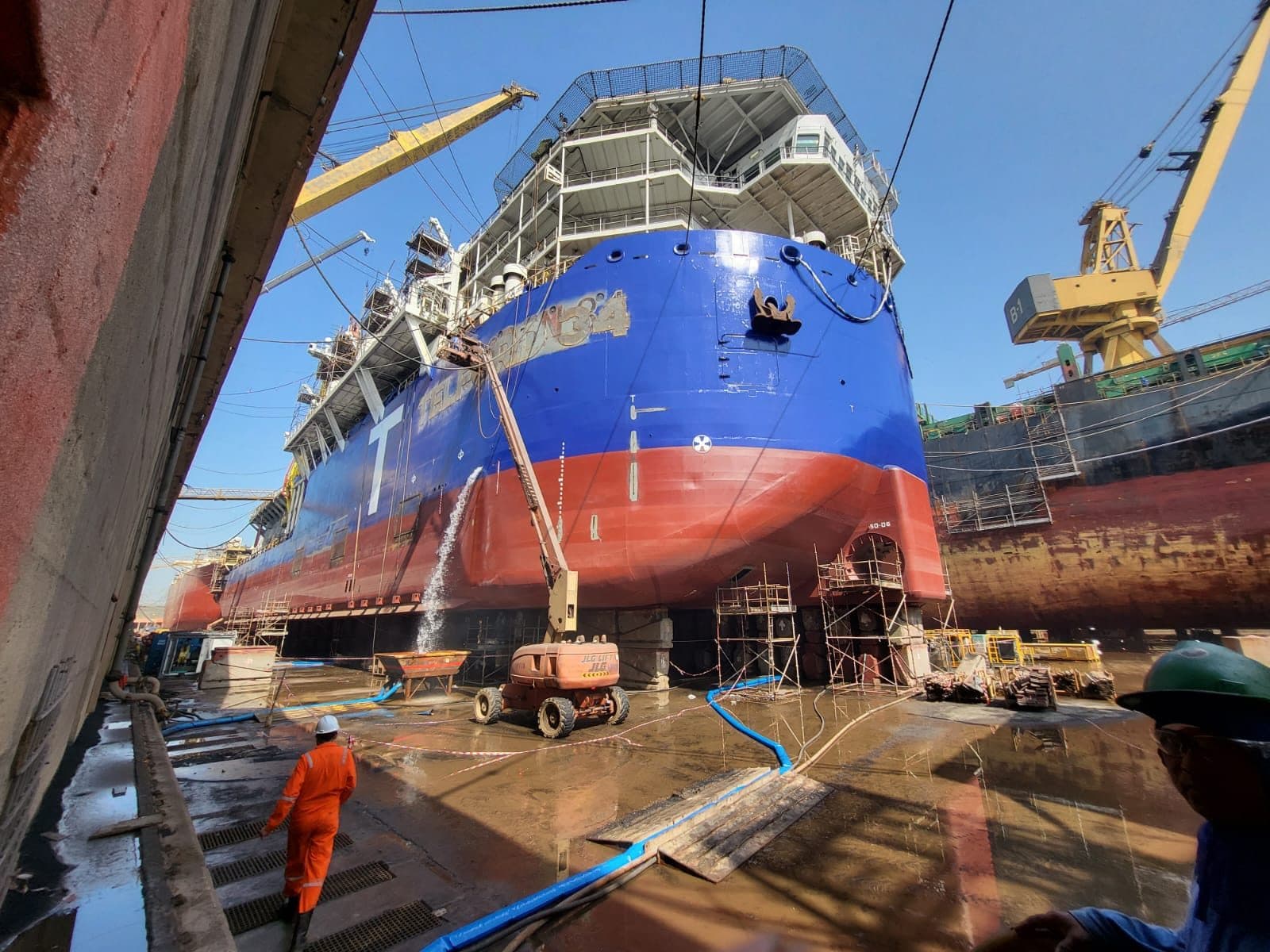 A commercial cargo vessel in drydock with an engineer at work